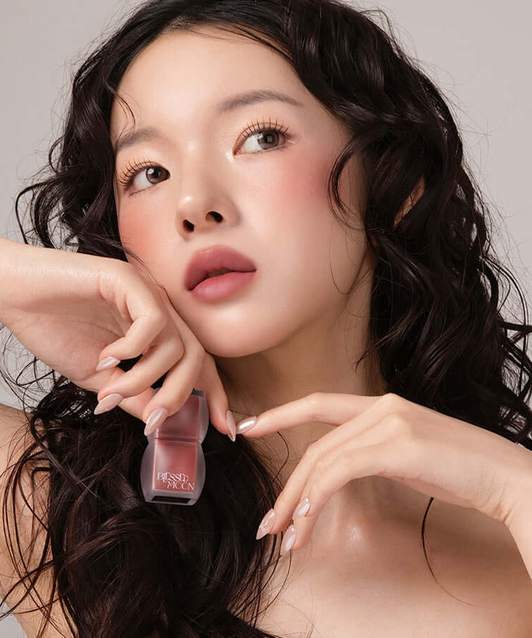 Model holding BLESSED MOON Veil Blur Lip Tint in a neutral makeup look
