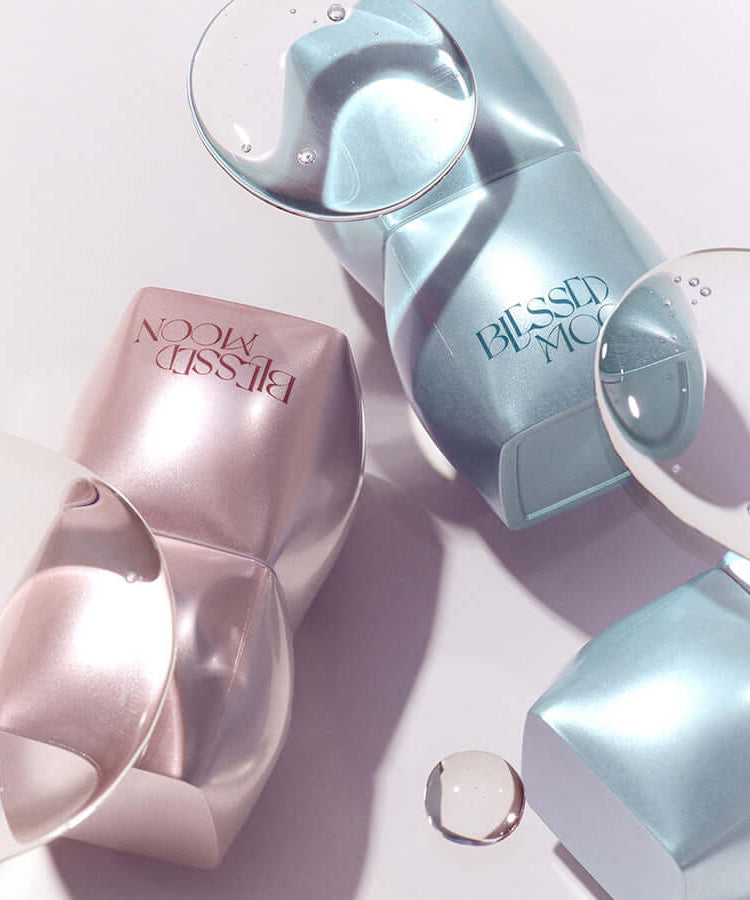 BLESSED MOON Veil Mood Lip Gloss bottles with reflective water droplets on a smooth surface.