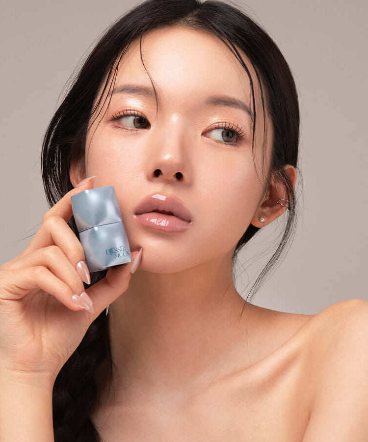 Woman holding BLESSED MOON Veil Mood Lip Gloss, showcasing glossy lips and product packaging.