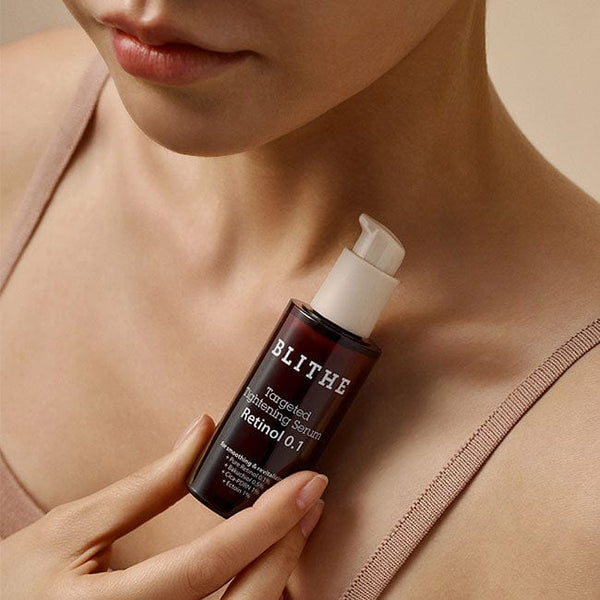 Woman holding BLITHE Targeted Tightening Serum Retinol 0.1 30ml bottle close to her neck.
