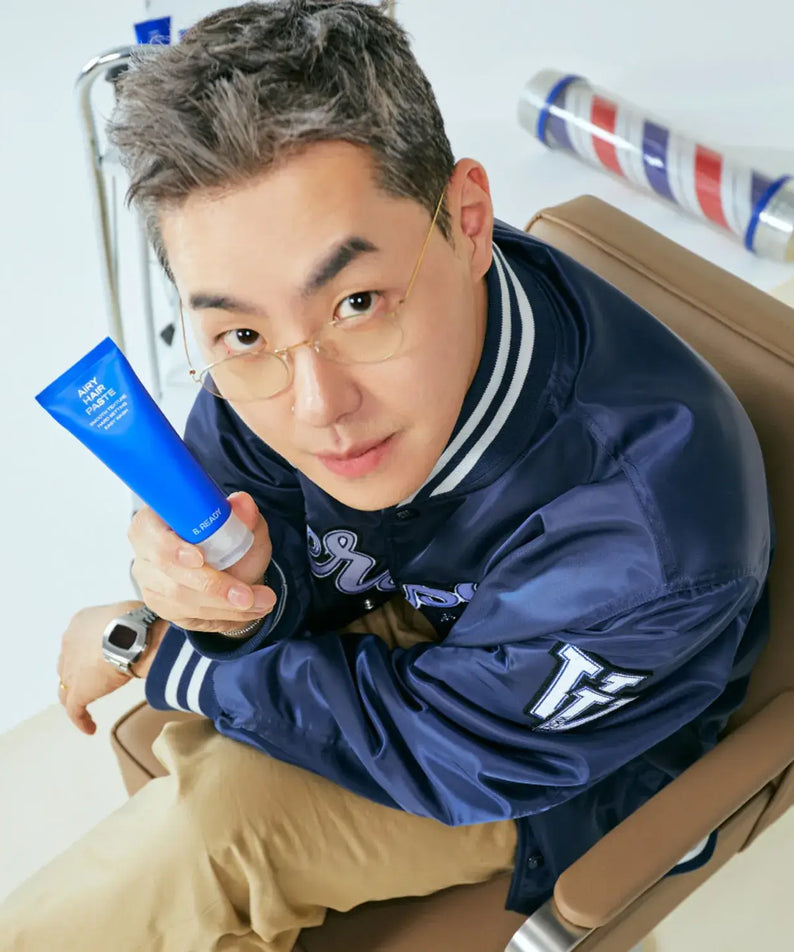 B.READY Airy Hair Paste 80g held by stylish Korean gentleman in barber chair — Gentleman Korea product shot for men’s hairstyling