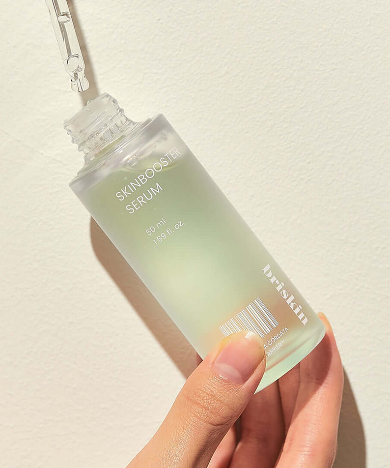 Hand holding BRISKIN Houttuynia Cordata Exo-Barrier Skinbooster Serum 50ml bottle against a light background