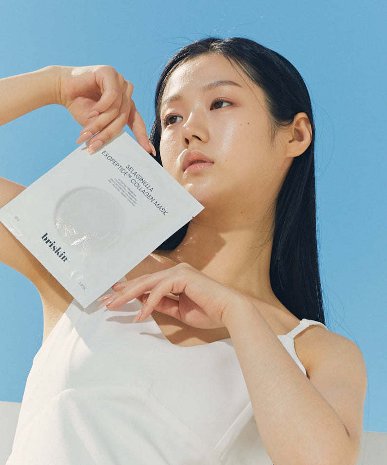 Woman holding BRISKIN Selaginella Exopeptide Collagen Mask 5 sheets against blue sky