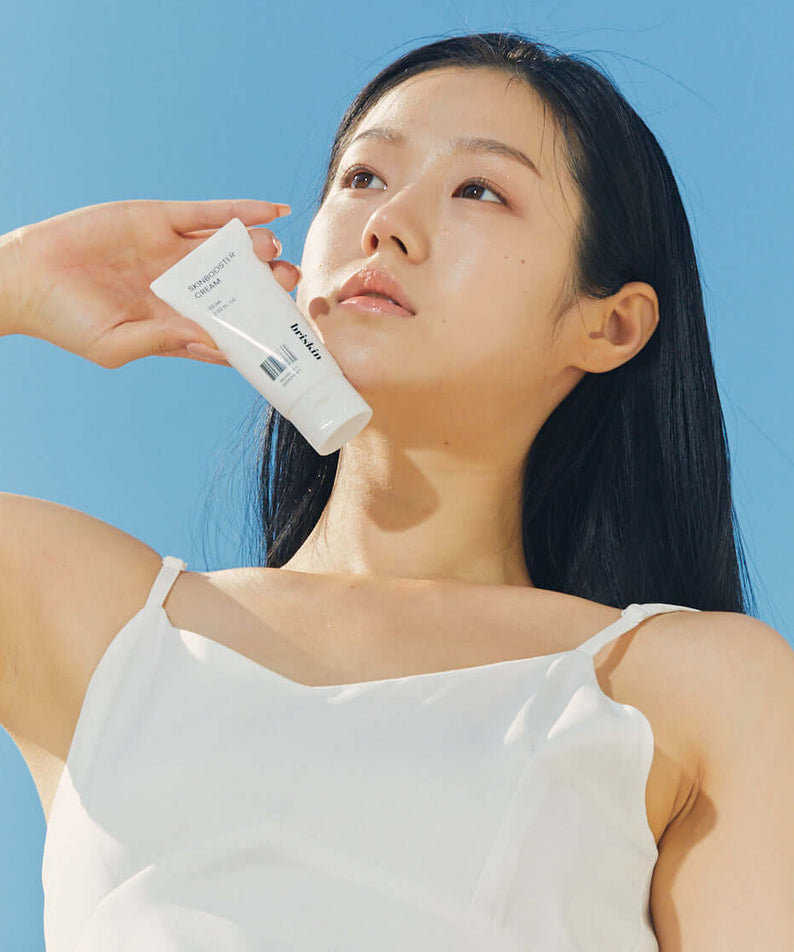 Woman holding BRISKIN Selaginella Exopeptide Skin Booster Cream 60ml against blue sky