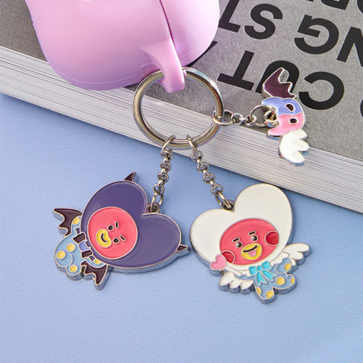 BT21 Angel & Villain Metal Key Ring sur un livre avec personnages en métal colorés. Accessoire mignon et tendance.