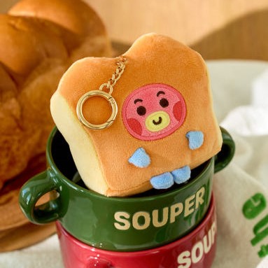 BT21 Bakery Plushy Keyring adorable et coloré posé sur une tasse verte, parfait pour les fans de BT21 et amateurs de porte-clés mignons.
