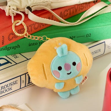 BT21 Bakery Plushy Keyring adorable peluche porte-clés sur des livres colorés