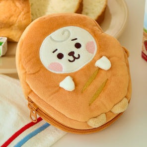 BT21 Bakery Pouch adorable poche en peluche thème boulangerie orange avec fermeture éclair, posée près de tranches de pain.
