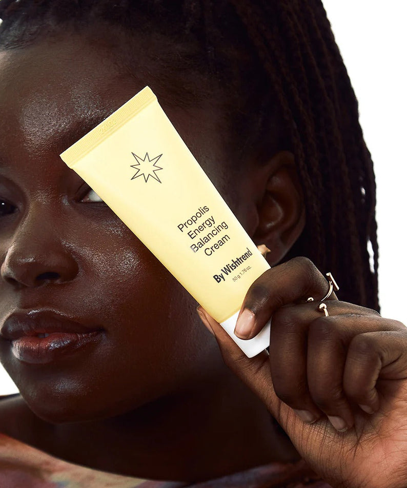 Person holding BY WISHTREND Propolis Energy Balancing Cream 50g tube showcasing skincare product packaging.