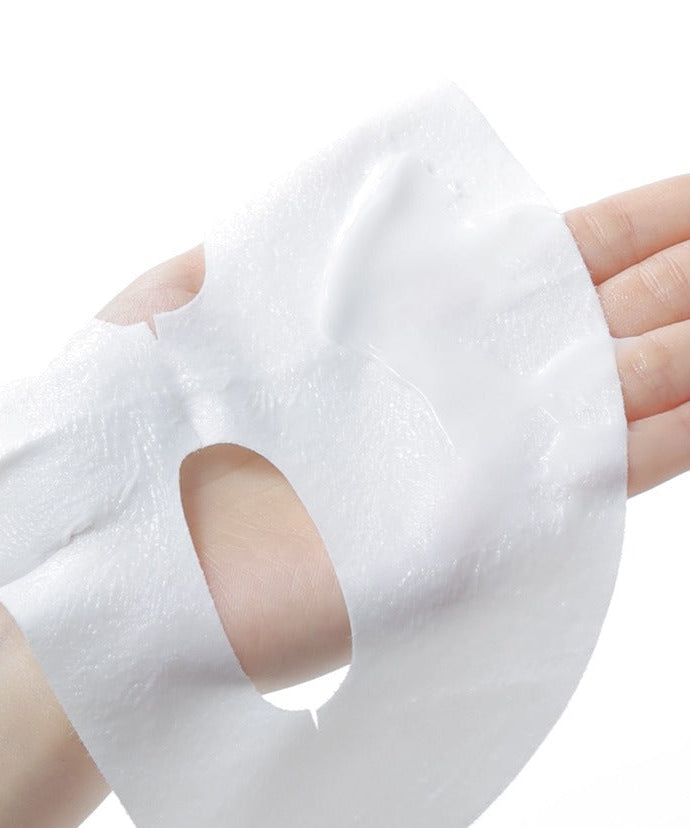 Hand holding CELIMAX Brightening Pore Blemish Cream Wrapping Mask 1 Sheets showing texture and application.