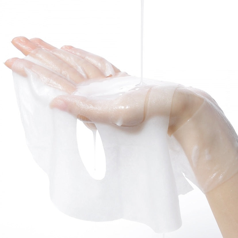 A hand holding a CELIMAX Brightening Pore Blemish Serum Mask sheet with serum dripping, showcasing hydrating and clarifying properties.