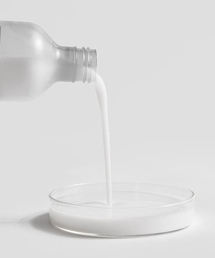 CELIMAX Dual Barrier Creamy Toner 150ml being poured into a clear dish on a white background, highlighting its creamy texture.