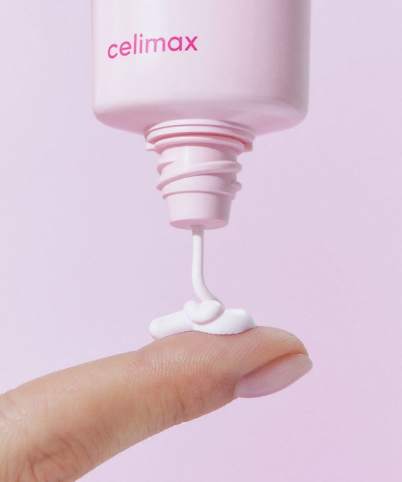 CELIMAX Heart Pink Tone-up Sun Cream 40ml being applied to a fingertip, showcasing its texture and packaging.