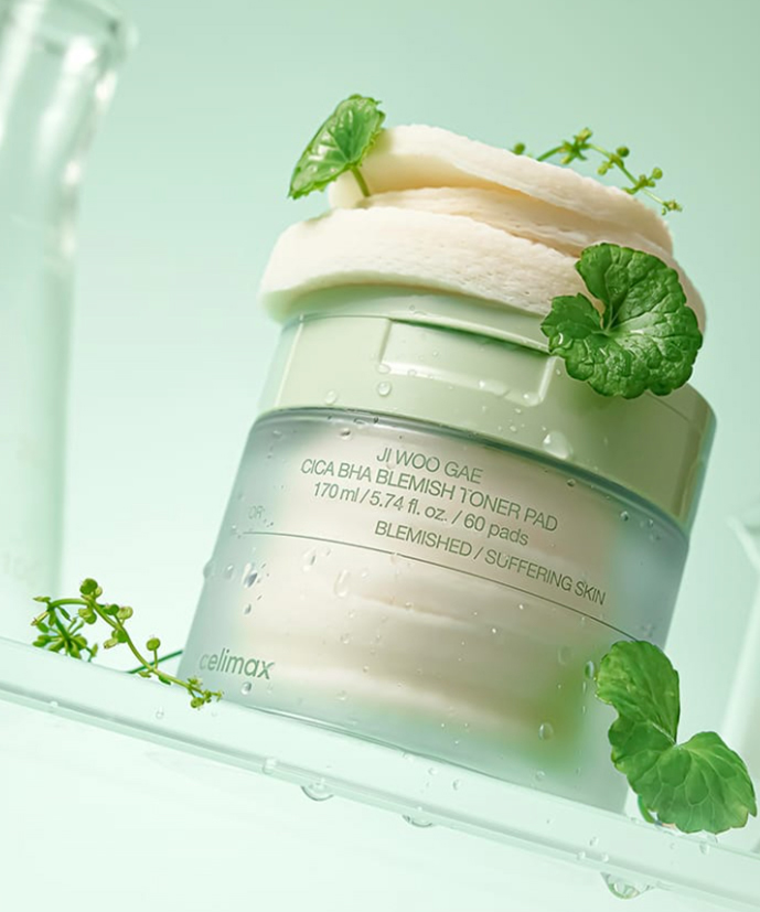 CELIMAX Ji Woo Gae Cica BHA Blemish Toner Pad 60 pads in a stylish green jar, surrounded by natural plant elements.