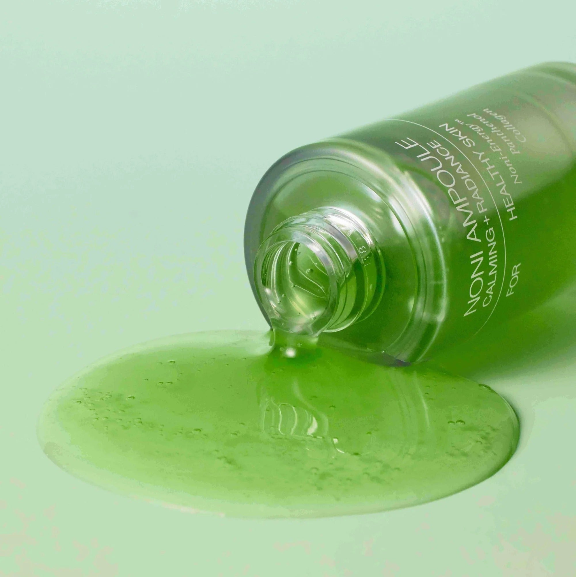 CELIMAX Noni Ampoule Calming+Radiance 100ml spilled on green surface showcasing texture and color