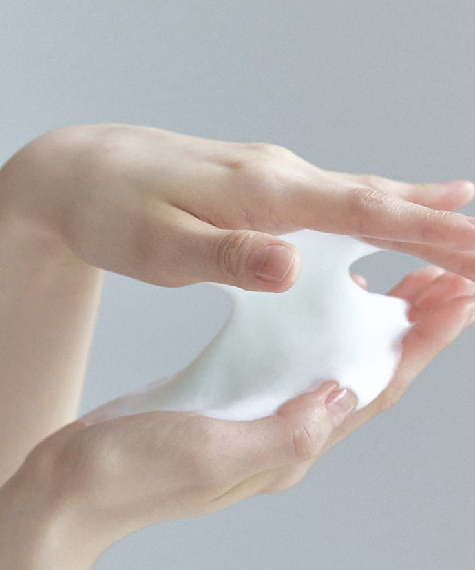 Hands holding foam from CELIMAX The Real Noni Acne Bubble Cleanser 155ml