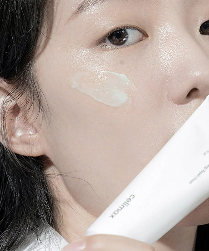 Woman applying CELIMAX The Real Noni Energy Repair Cream 50ml to her face.
