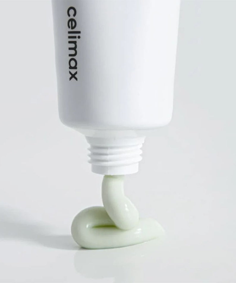 CELIMAX The Real Noni Energy Repair Cream 50ml being dispensed from a tube, showcasing texture and color against a clean background.