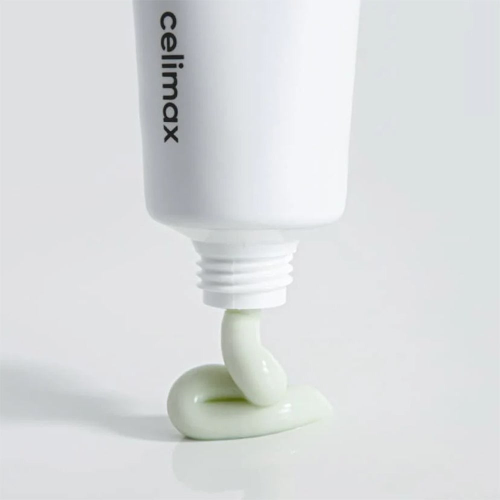 CELIMAX The Real Noni Energy Repair Cream 50ml being dispensed from a tube, showcasing texture and color against a clean background.