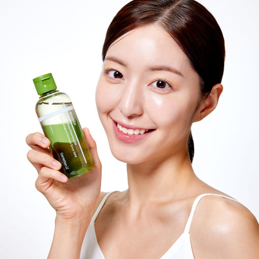 Woman holding CENTELLIAN 24 Madeca Matcha Cleansing Oil 200ml bottle, showcasing skincare product