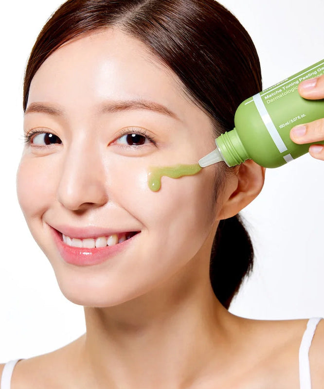 Smiling woman applying CENTELLIAN 24 Madeca Matcha Toning Peeling Gel 150ml to her face from a green bottle.
