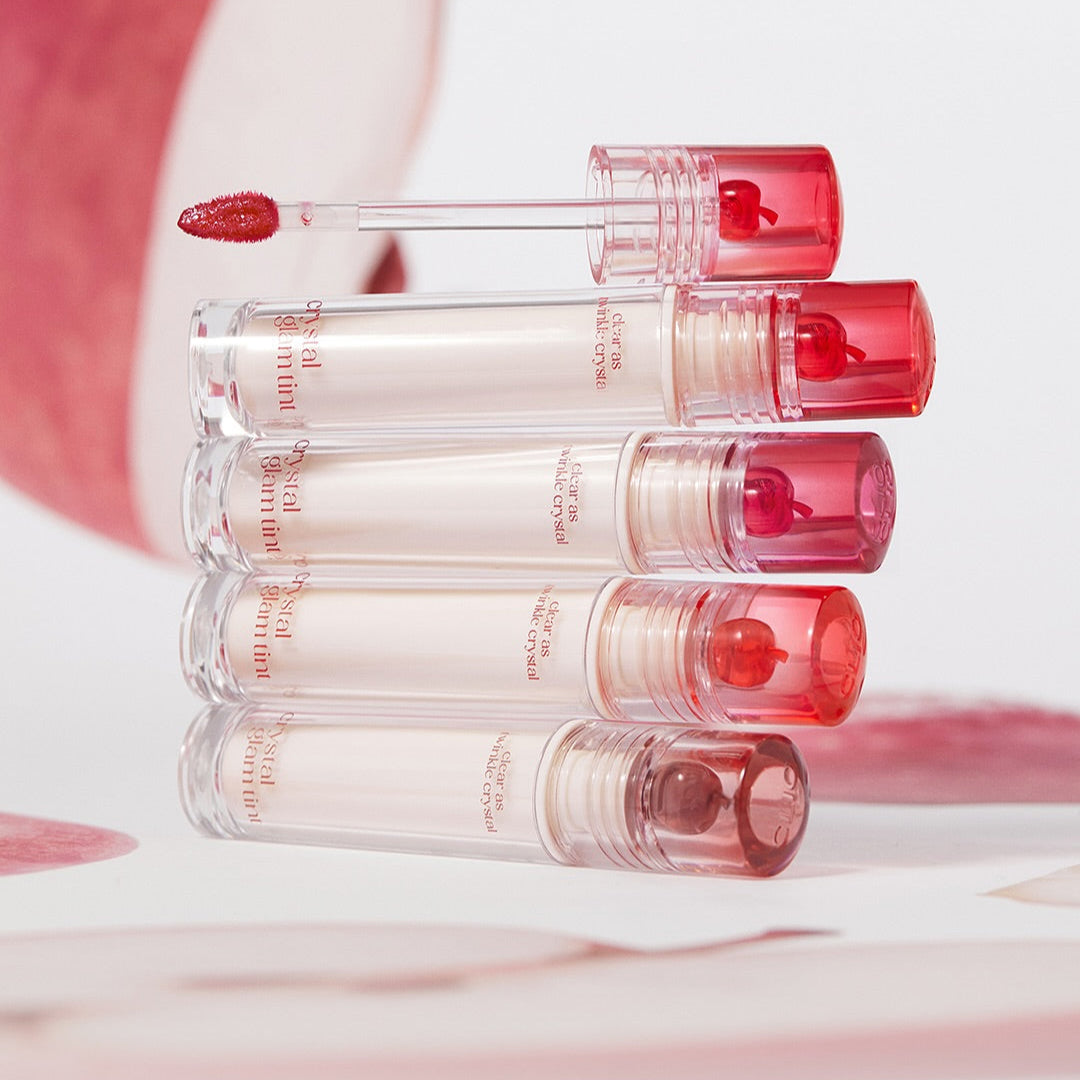 Five tubes of CLIO Crystal Glam Tint lip tint stacked neatly with shades visible, showcasing vibrant makeup colors.