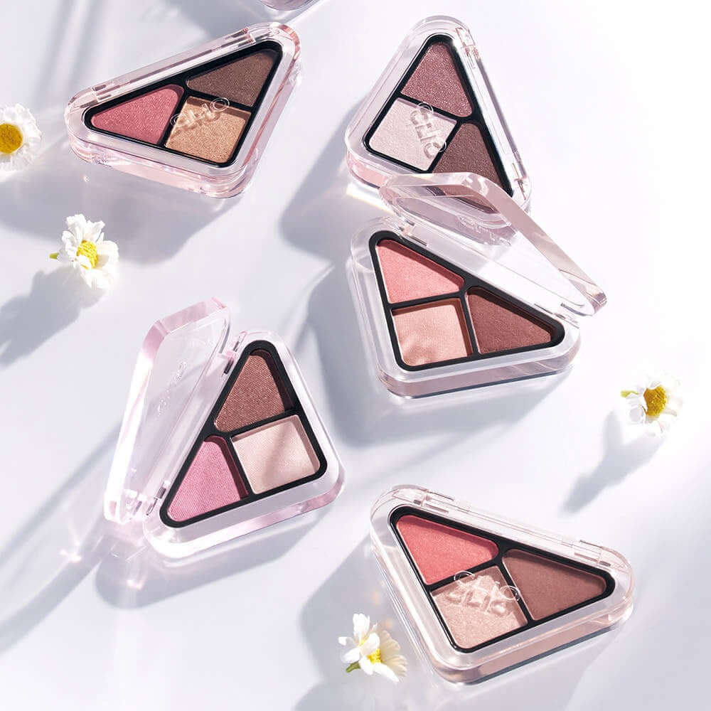 CLIO Essentail Shadow Tab makeup palettes with delicate colors and compact design, surrounded by small flowers on a white background.