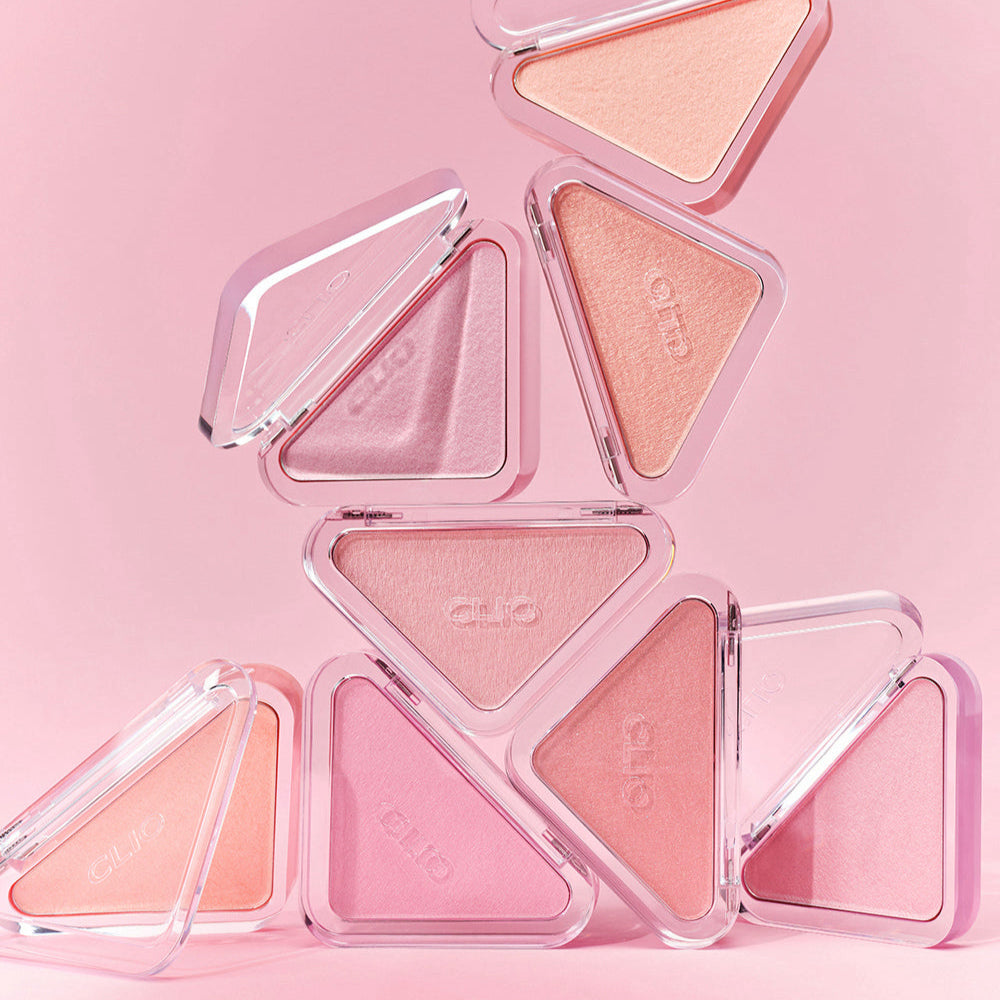 A collection of CLIO Essential Blush Tab products in various pink shades against a pink background, showcasing their elegant design.
