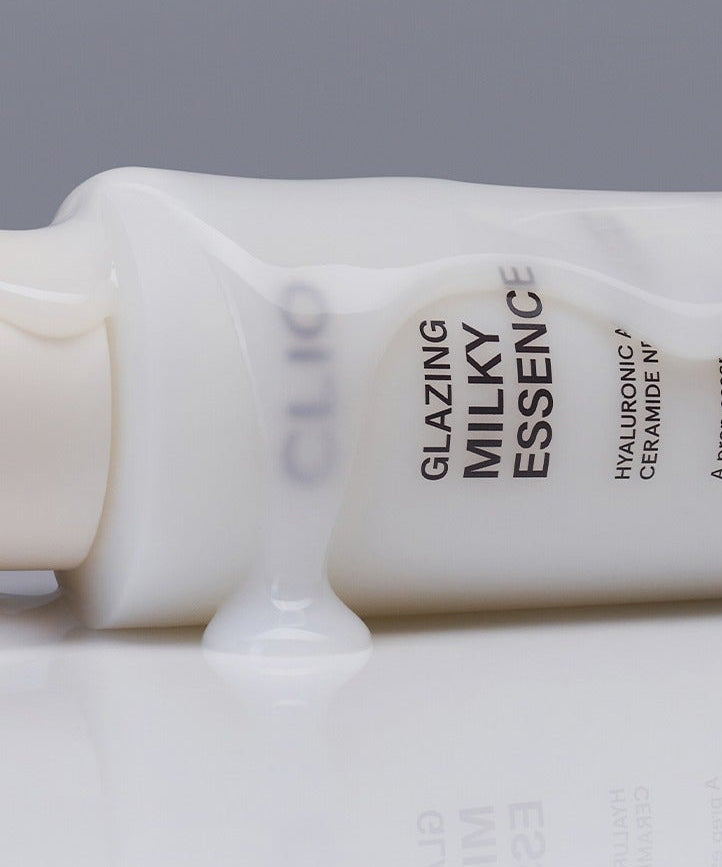 CLIO Glazing Milky Essence 120ml bottle with milky texture spilling, showcasing product's luxurious essence for skin care.