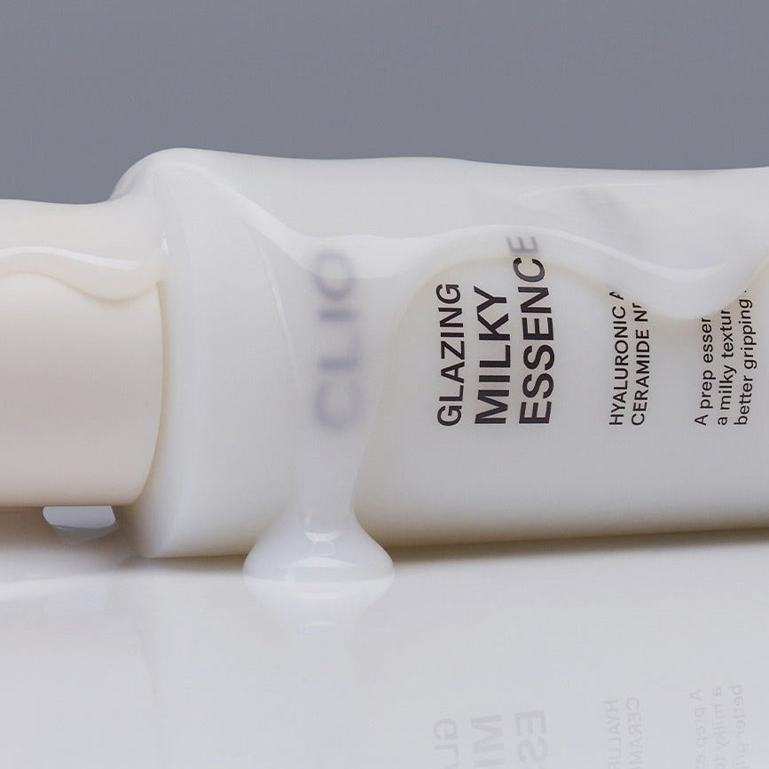CLIO Glazing Milky Essence 120ml bottle with milky texture spilling, showcasing product's luxurious essence for skin care.