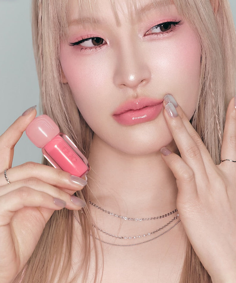 Model showcasing CLIO Volume Mate Blur Tint/Gloss with a pink hue, highlighting its glossy finish and vibrant color.