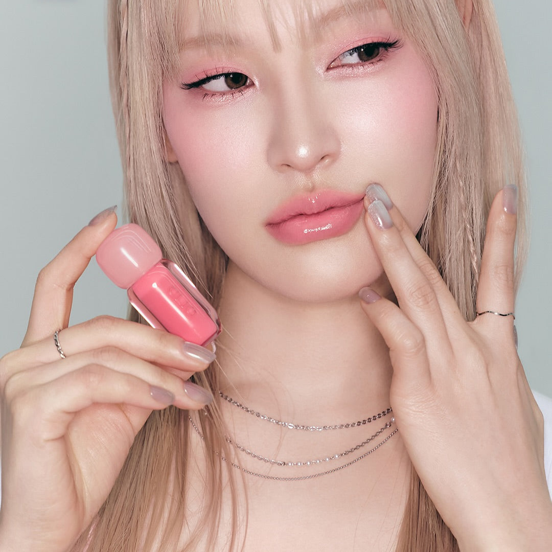 Model showcasing CLIO Volume Mate Blur Tint/Gloss with a pink hue, highlighting its glossy finish and vibrant color.
