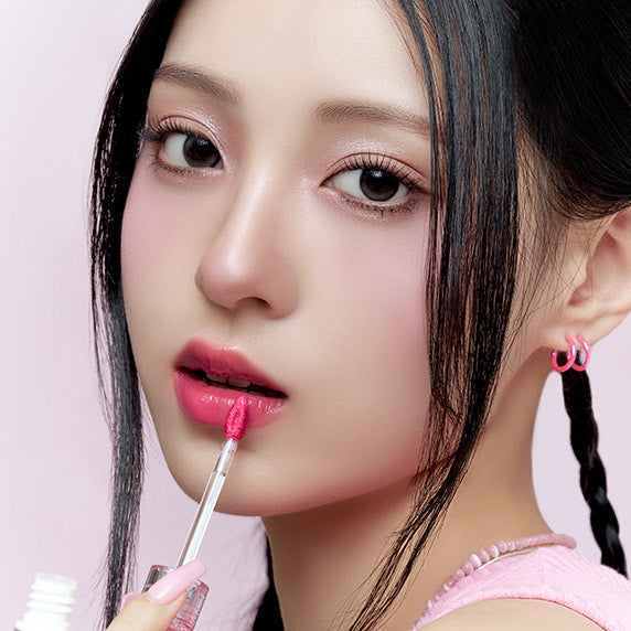 Woman applying pink CLIO Crystal Glam Tint on lips for a glamorous look.