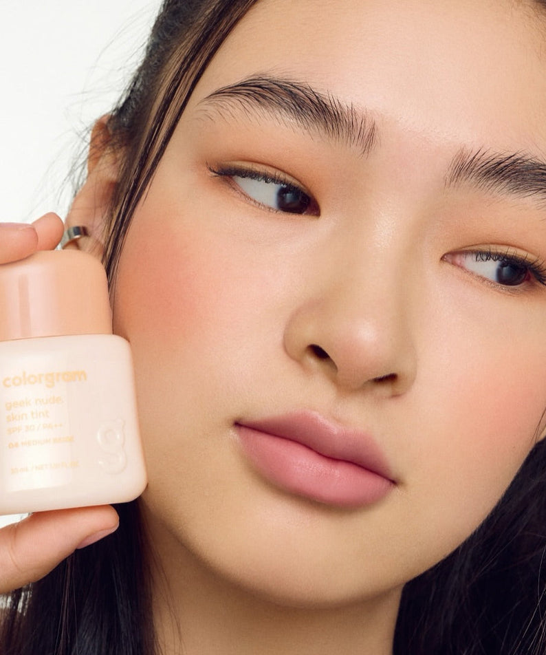 Person holding a bottle of COLORGRAM Geek Nude SKin Tint 30ml against skin.