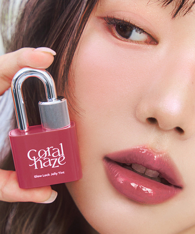 Close-up of model holding CORALHAZE Glow Lock Jelly Tint, showcasing glossy pink lips, highlighting product's vibrant color and shine.