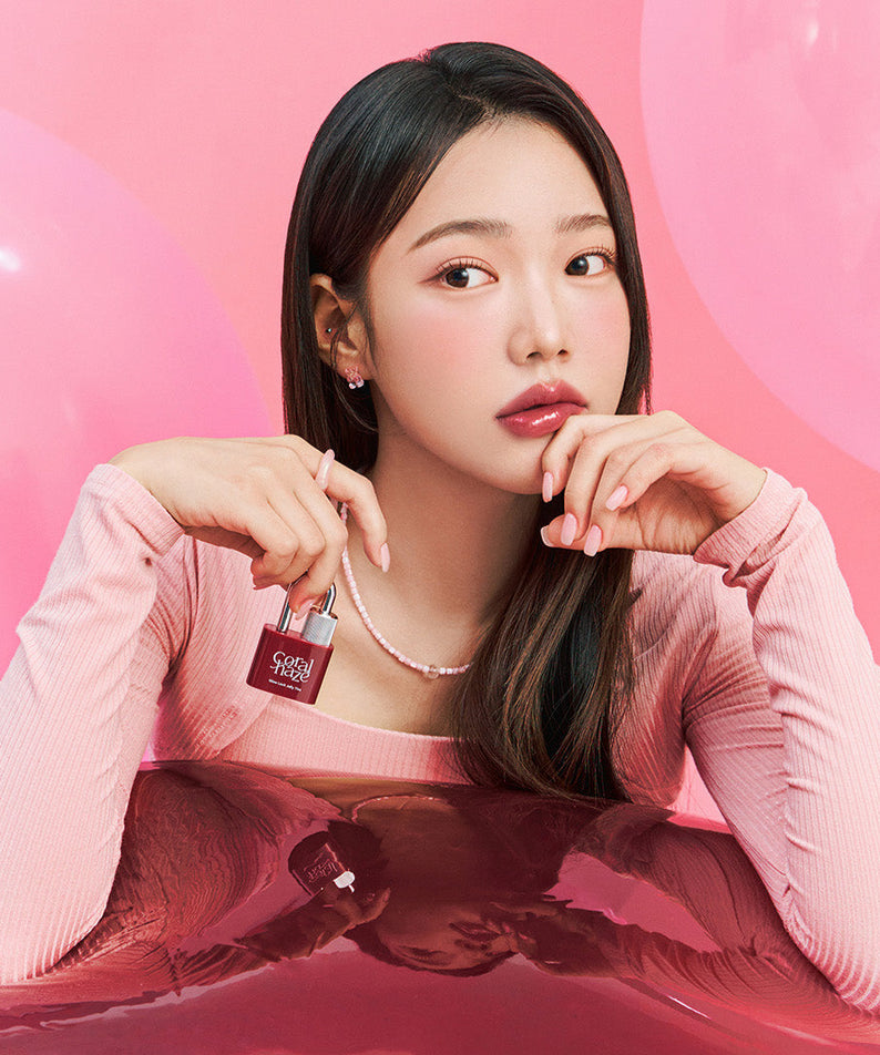 Model holding CORALHAZE Glow Lock Jelly Tint in a pink aesthetic setting with balloons in the background.