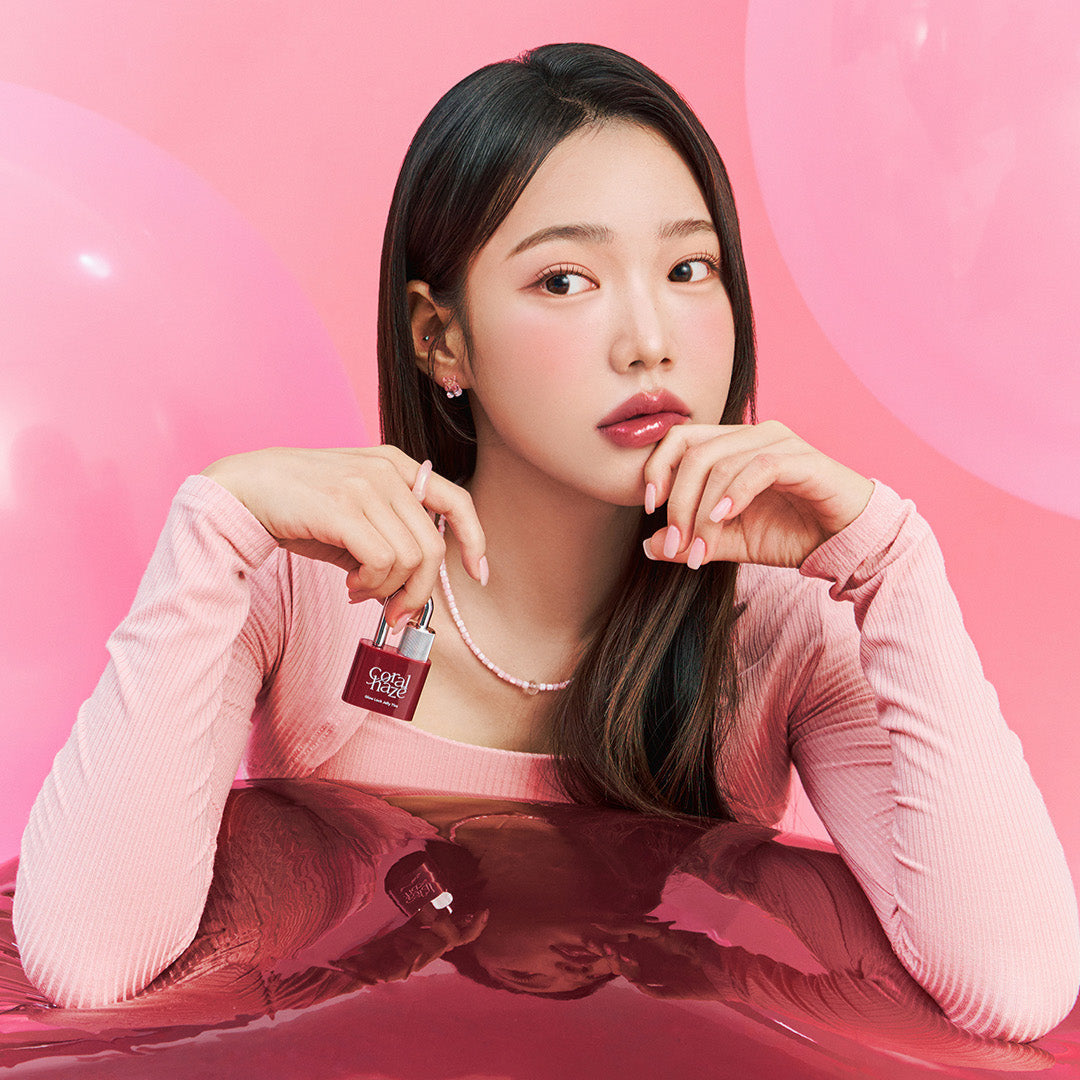 Model holding CORALHAZE Glow Lock Jelly Tint in a pink aesthetic setting with balloons in the background.