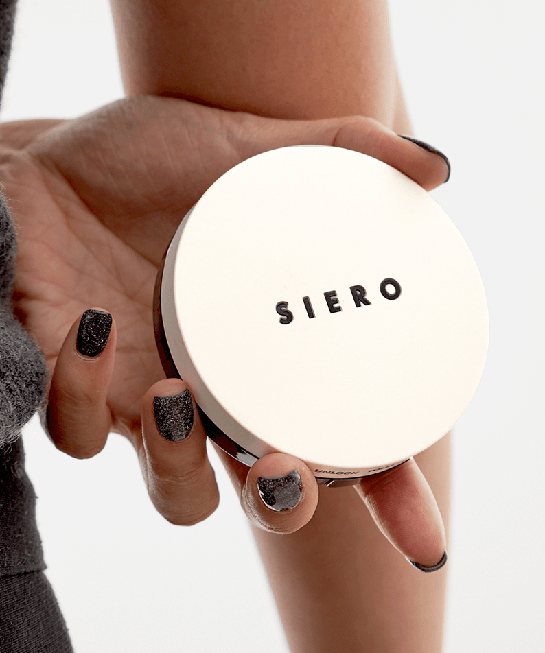 Hand holding COSIERO Coco Aqua Black Cushion in elegant packaging, showcasing premium cosmetic product.