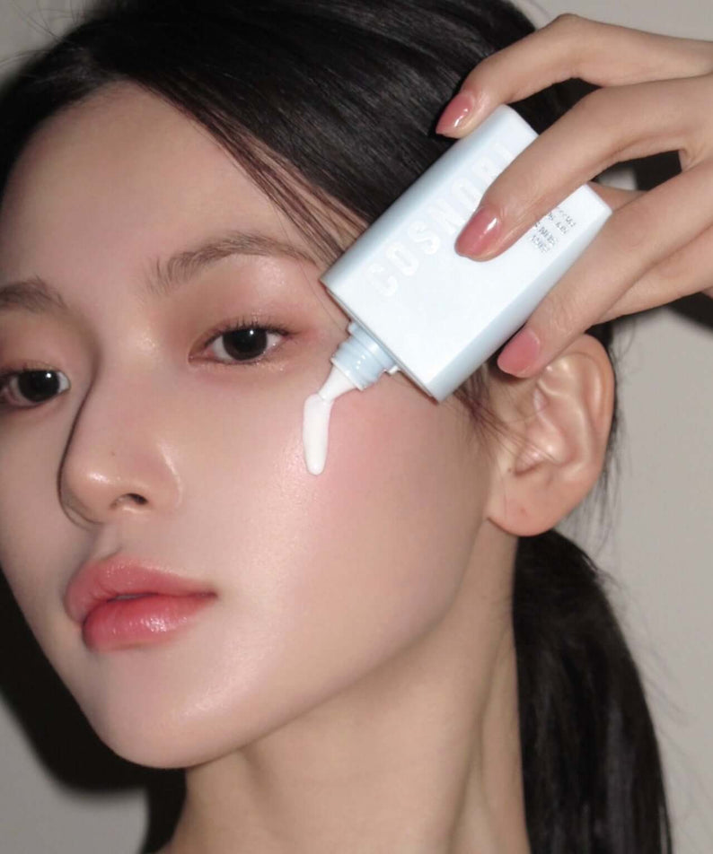 Woman applying COSNORI Airy Tone Up Sun Serum on her face for skincare