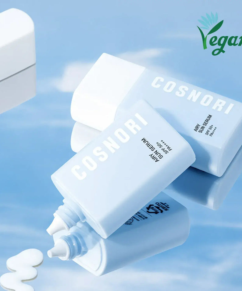 COSNORI Airy Tone Up Sun Serum bottles with vegan logo on a reflective surface