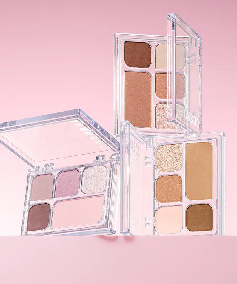 COSNORI My Moment Eye Palette featuring a range of neutral and shimmer eyeshadows in open compact cases on a pink background.