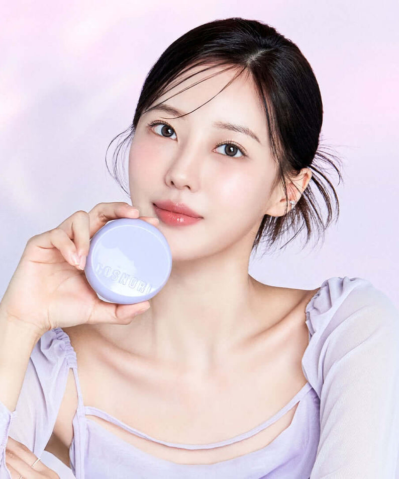 Woman holding a COSNORI Panthenol Barrier Cushion SPF50+PA++++ in a soft-lit setting. Enhance your skincare routine with this cushion.