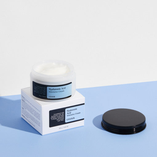 COSRX Hyaluronic Intensive Cream 100g in open jar with product packaging on blue surface
