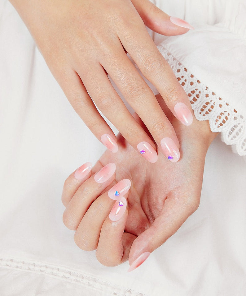 Woman's hands showcasing DASHING DIVA MAGIC PRESS Heart Cheek - Long Oval nails with pink and gem accents.