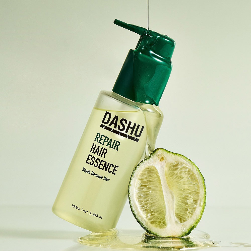 DASHU Daily Repair Hair Essence 100ml bottle with green cap next to a sliced lime, promoting hair repair benefits.