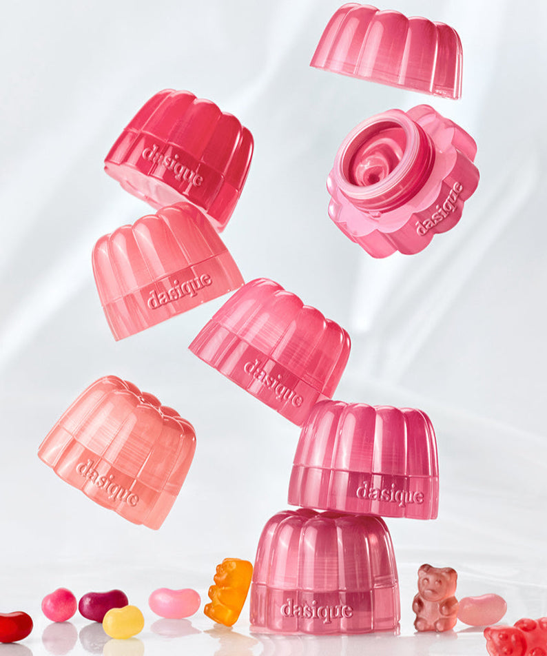 Stack of DASIQUE Chewing Glow Pot containers with various colorful jelly beans and gummy bear on a white background.