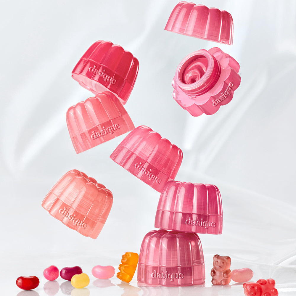 Stack of DASIQUE Chewing Glow Pot containers with various colorful jelly beans and gummy bear on a white background.