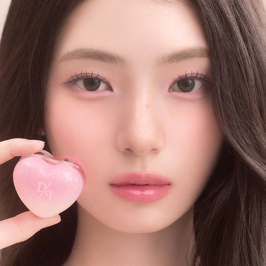 Model holding a heart-shaped pink DASIQUE Daisy Candy Rolling Pot for makeup