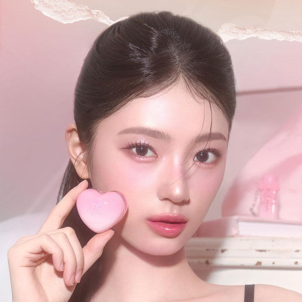 Person holding a heart-shaped beauty product, highlighting the DASIQUE Daisy Candy Rolling Pot aesthetics.
