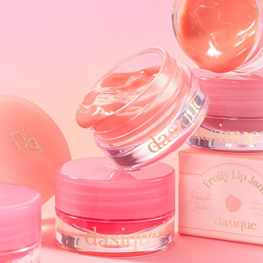 DASIQUE Fruity Lip Jam in peach and pink shades against a soft pink background, showcasing the product's texture and packaging.